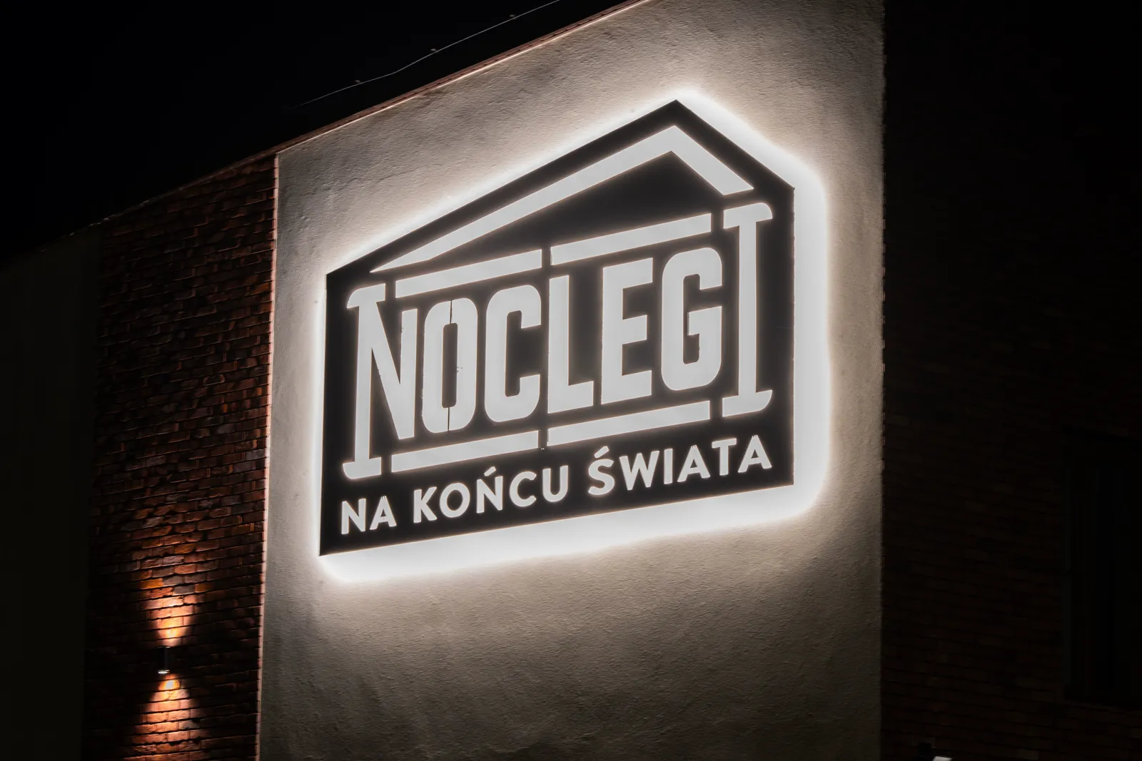 Podświetlony szyld Noclegi na końcu świata nocą