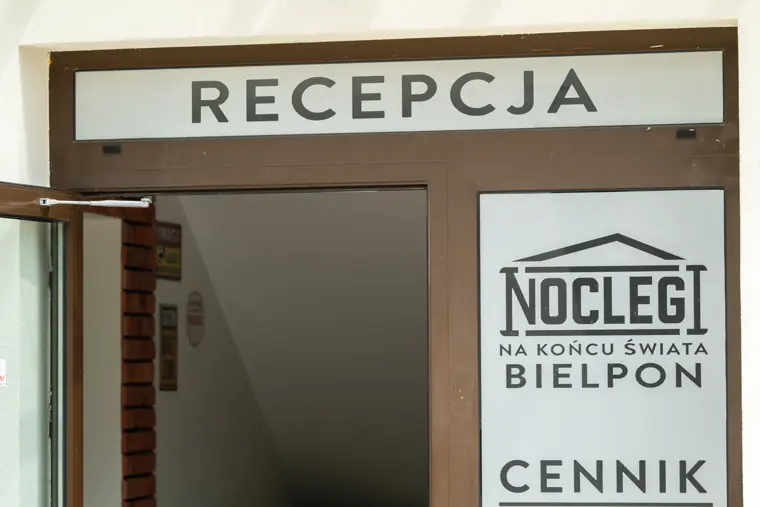 Wejście do recepcji z tablicą cennika